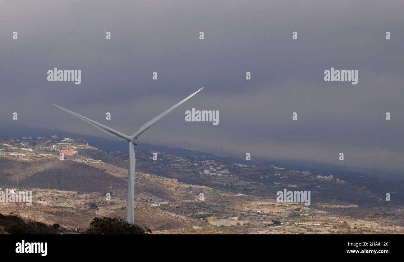 Wind turbine and landscape with houses and leaden sky Stock Photo