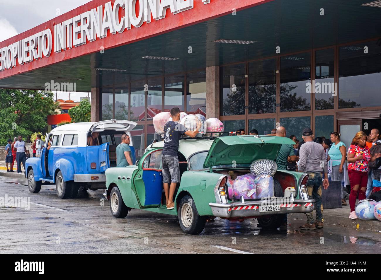 Cubans loading their old American cars with loads of imported foreign merchandise in front of the Antonio Maceo Airport in the city Santiago de Cuba Stock Photo