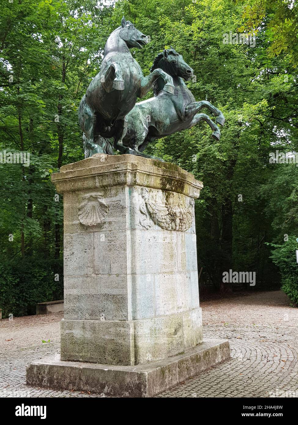 bavariapark on theresienwiese,laid out by king ludwig i between 1825 - 1831,large lawn,lush trees. a tour takes you past numerous sculptures,including these bronze horses,pedestals with scallops. Stock Photo