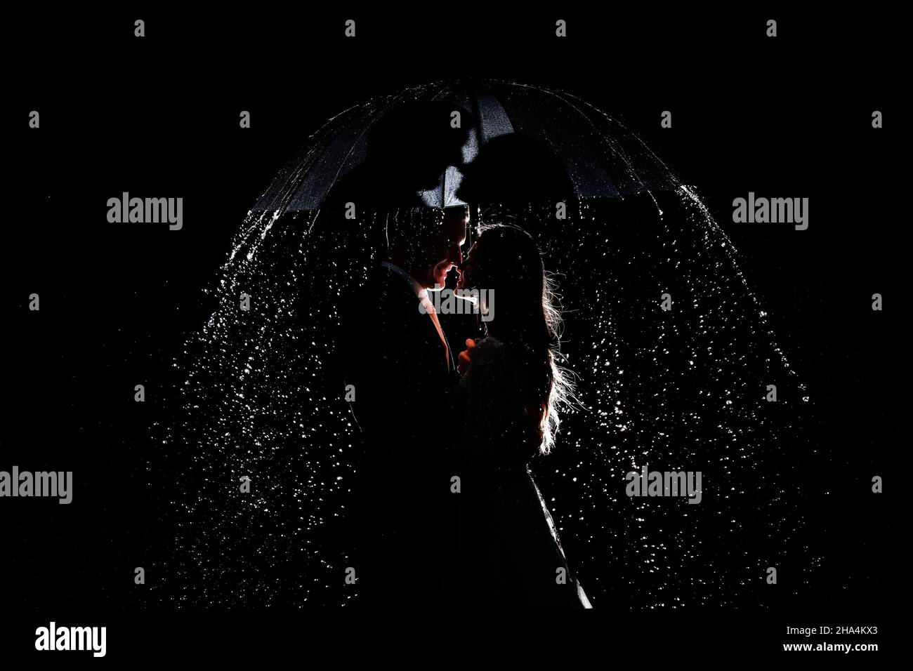 Love in the rain. Silhouette of kissing couple under umbrella. couple ...