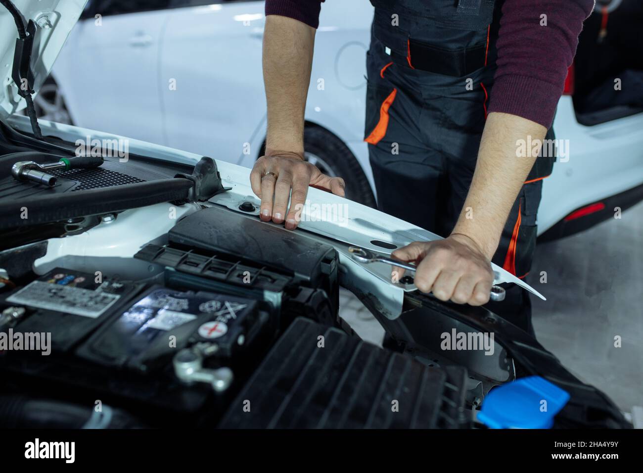 Car service. An auto mechanic is standing near the car with a tool in