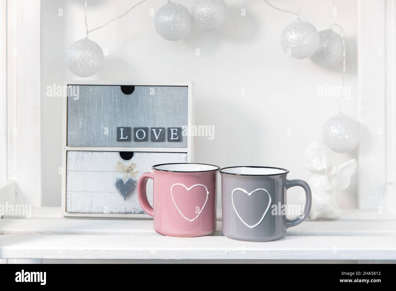 Small chest of drawers with two drawers with the words 'love'. Pink and gray cup with heart for Valentine's Day Stock Photo