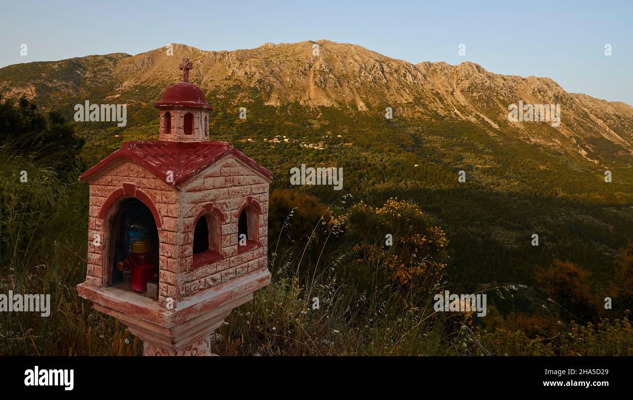 greece,greek islands,ionian islands,lefakada or lefkas,mountain landscape southwest,late afternoon light,in the foreground miniature chapel in the shade,green hills,in the background mountain ridges lit by the sun Stock Photo