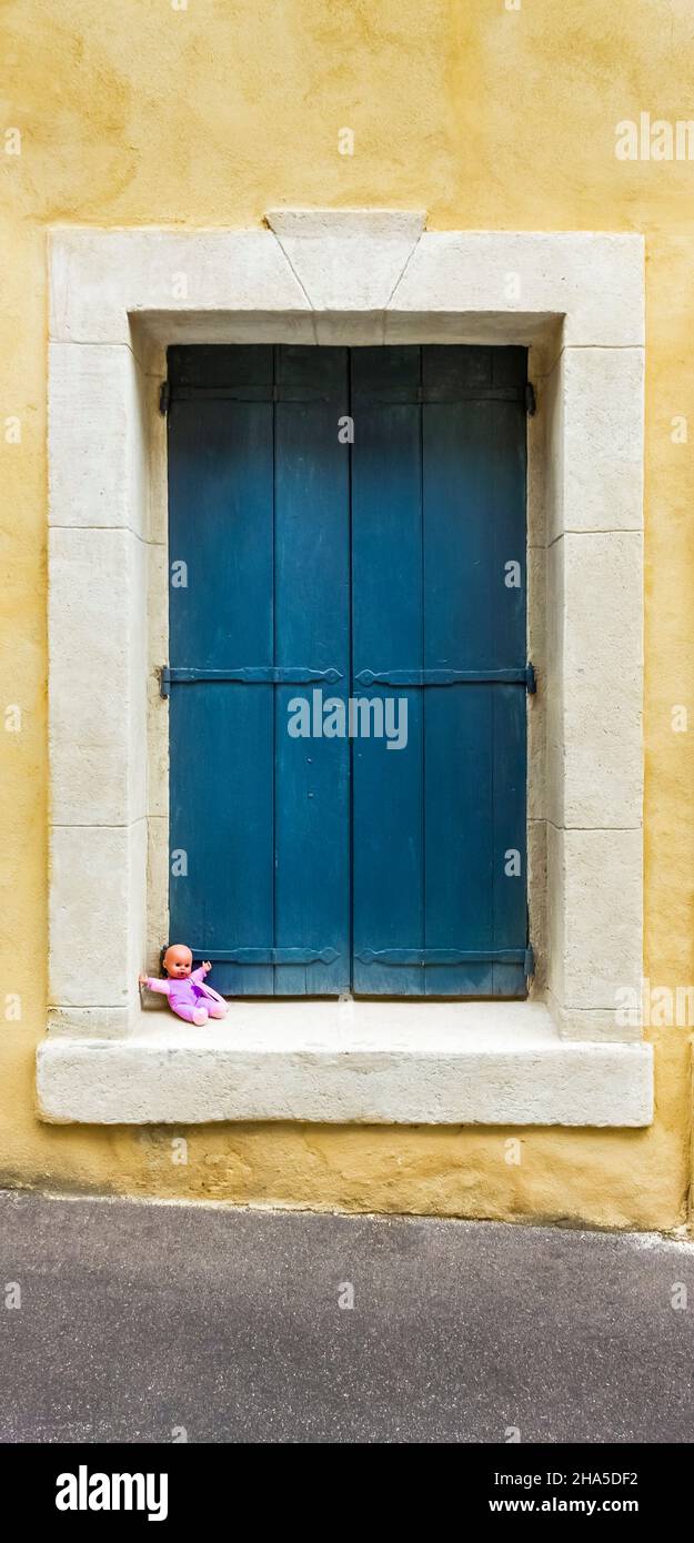seated doll in a window frame in fleury d'aude. Stock Photo