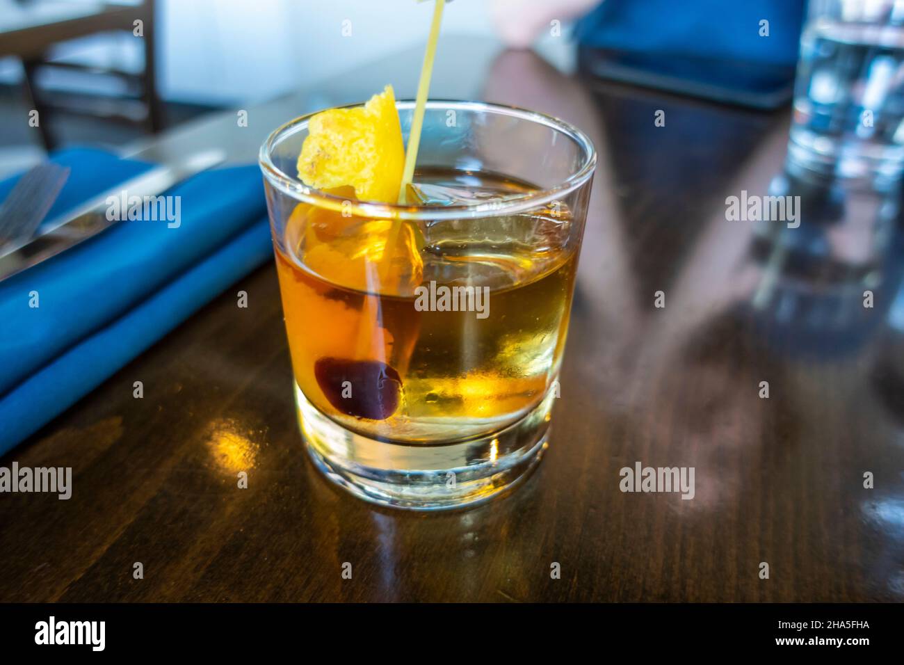 old fashioned whiskey drink in a cocktail glass with ice on a wood table in a restaurant bar Stock Photo