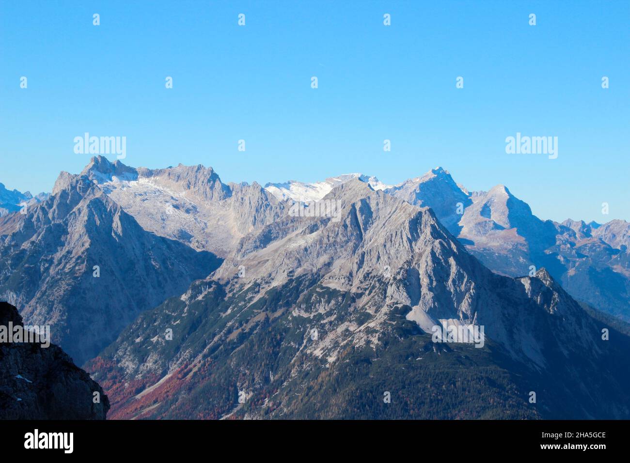 view from karwendel,karwendelbahn mountain station to the wetterstein mountains,with wetterstein,wettersteinspitzen,alpspitze,zugspitze,wetterstein massif in the foreground the grünkopf above mittenwald,in front of blue sky,germany,bavaria,upper bavaria, Stock Photo