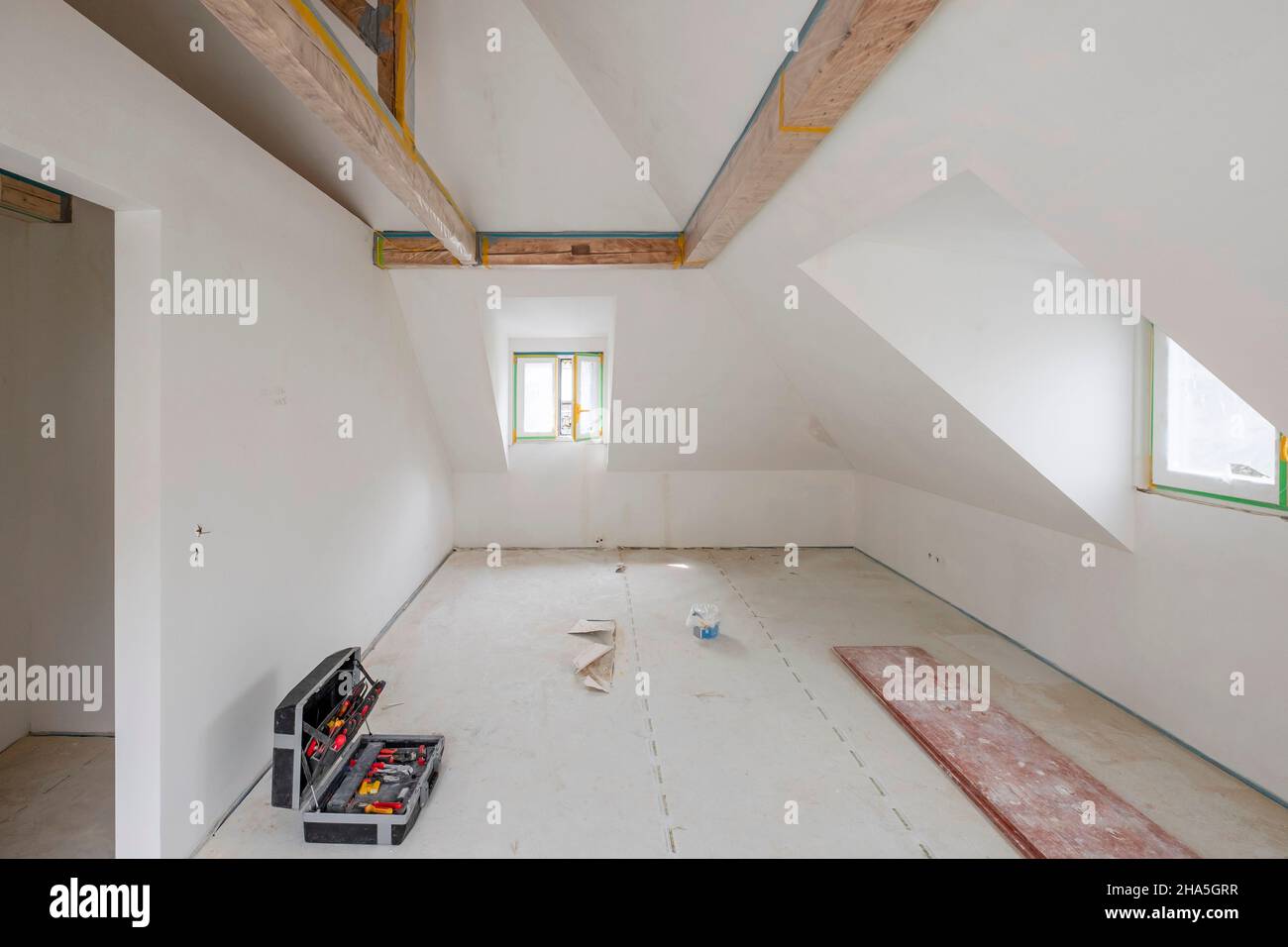 construction site,refurbishment and renovation of an apartment,empty room in the attic with wooden beam ceiling and dormer Stock Photo