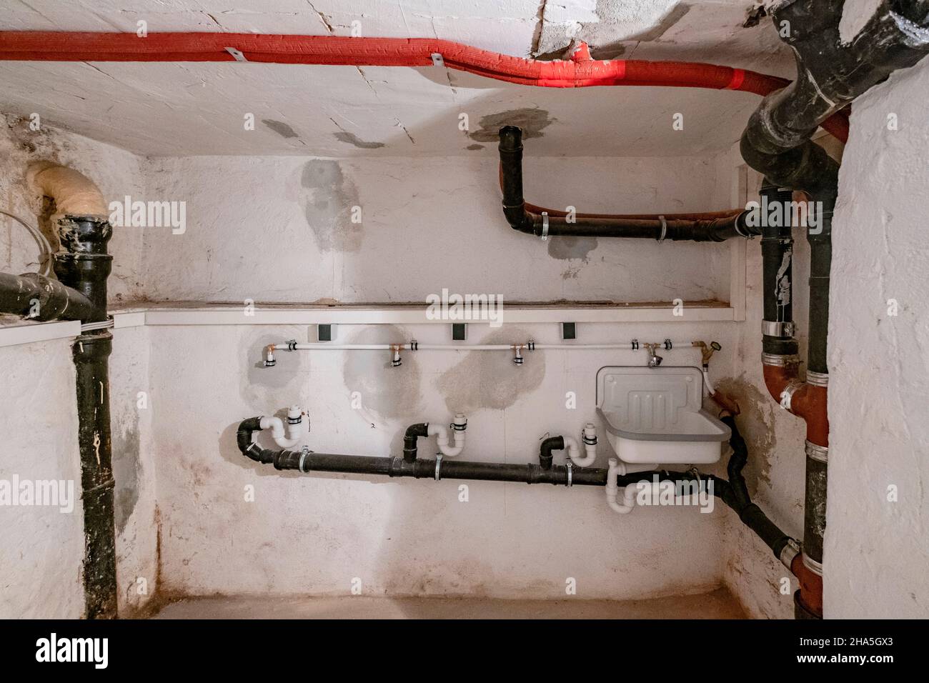 construction site,redevelopment and renovation of an apartment,empty room of a laundry room in the basement with old sewer pipes Stock Photo