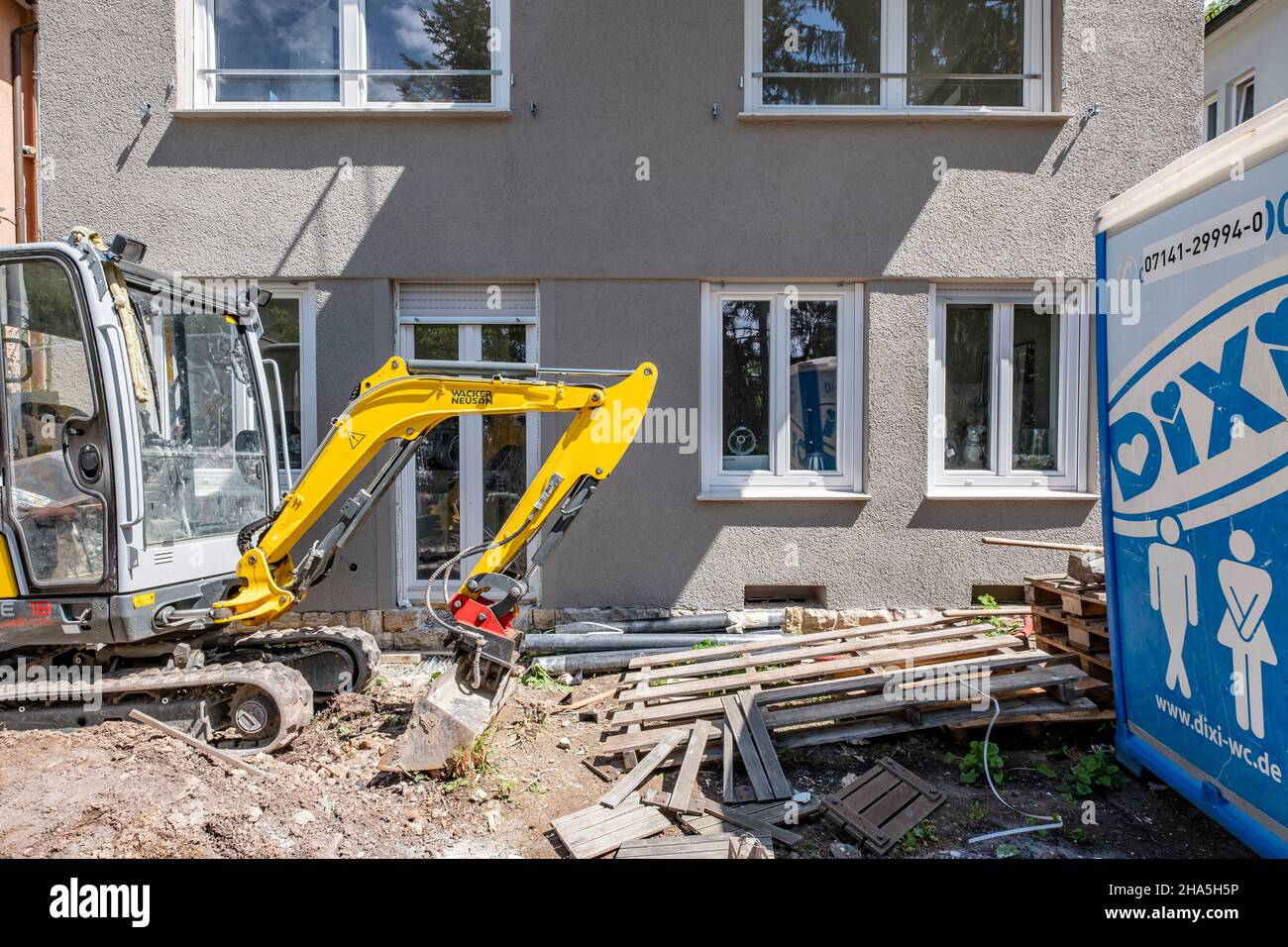 construction site,renovation and renovation of an apartment,small excavator stands in front of a renovated house Stock Photo