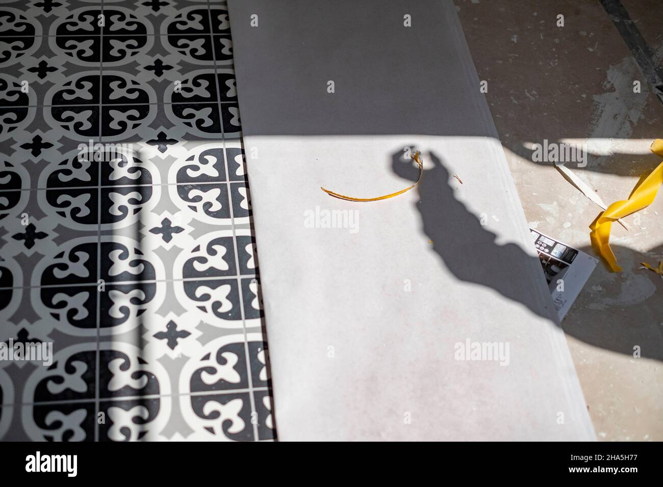 construction site,redevelopment and renovation of an apartment,detail of the shadow of a craftsman on a floor with tiles Stock Photo