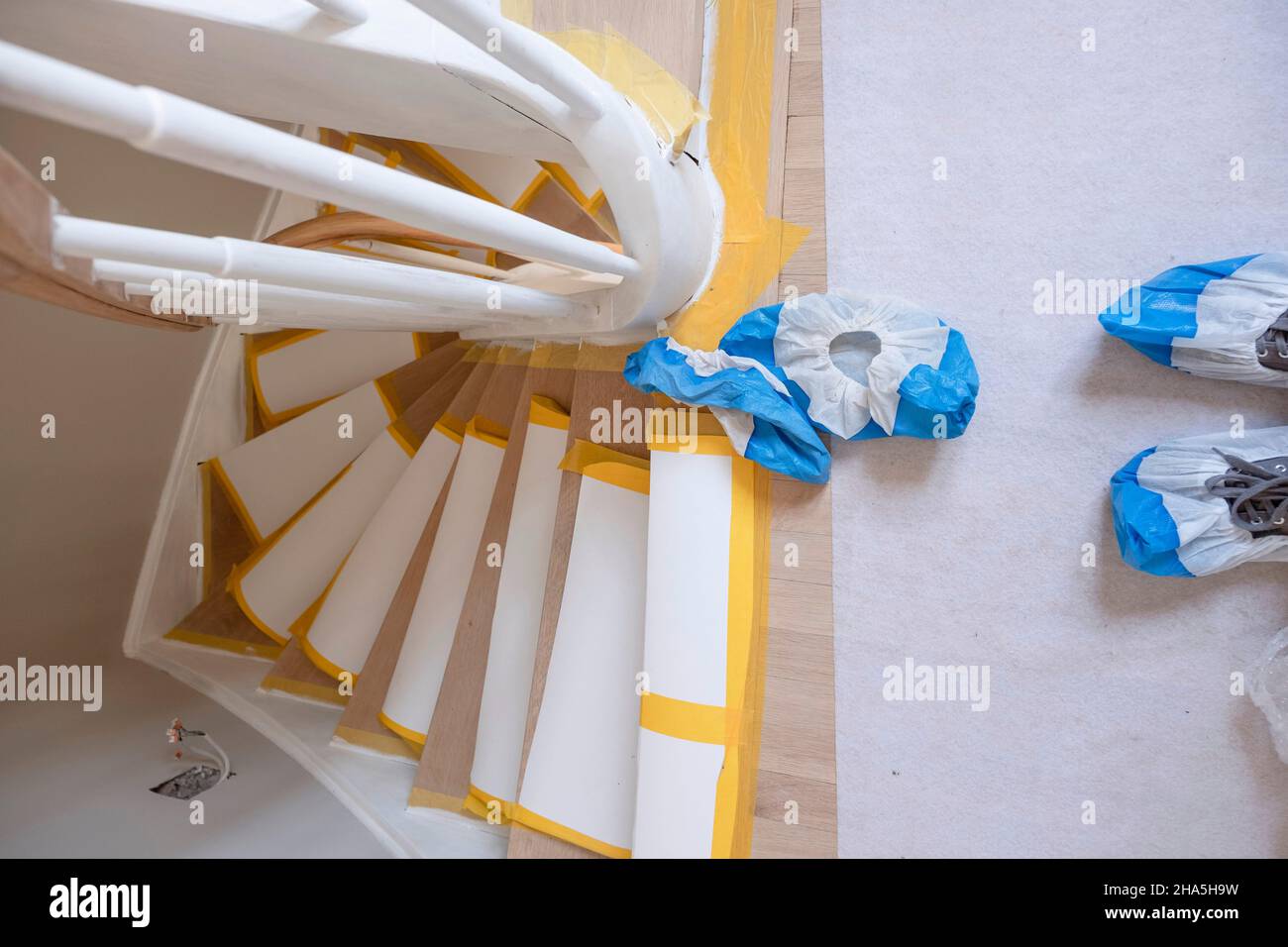 construction site,refurbishment and renovation of an apartment,covered steps in the stairwell of an old building and blue overshoes Stock Photo