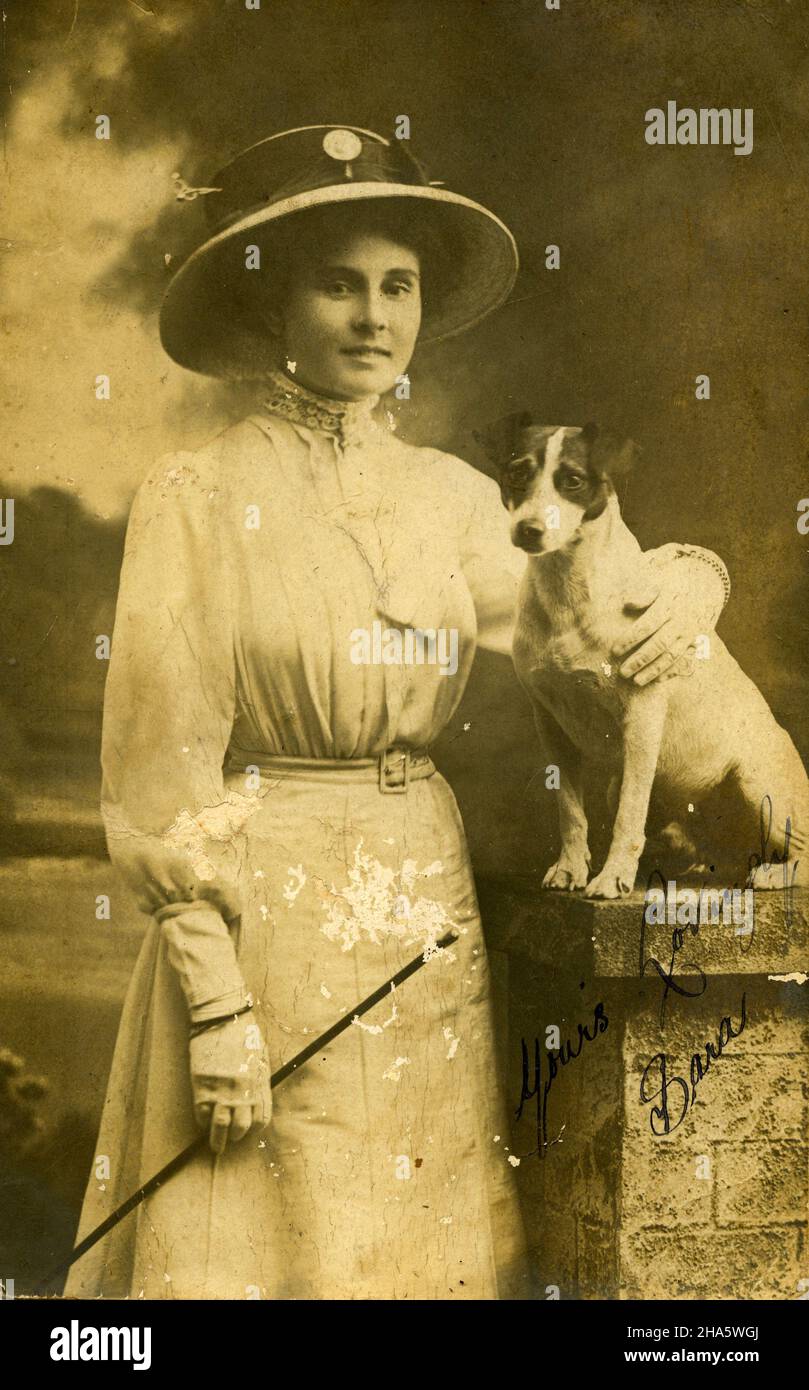 studio portrait of a modestly dressed young woman with a dog, inscribed Yours lovingly, Sara; circa 1900 Stock Photo