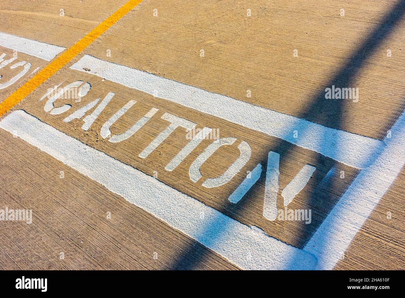 The word caution spelled out in white paint on the sidewalk. Stock Photo
