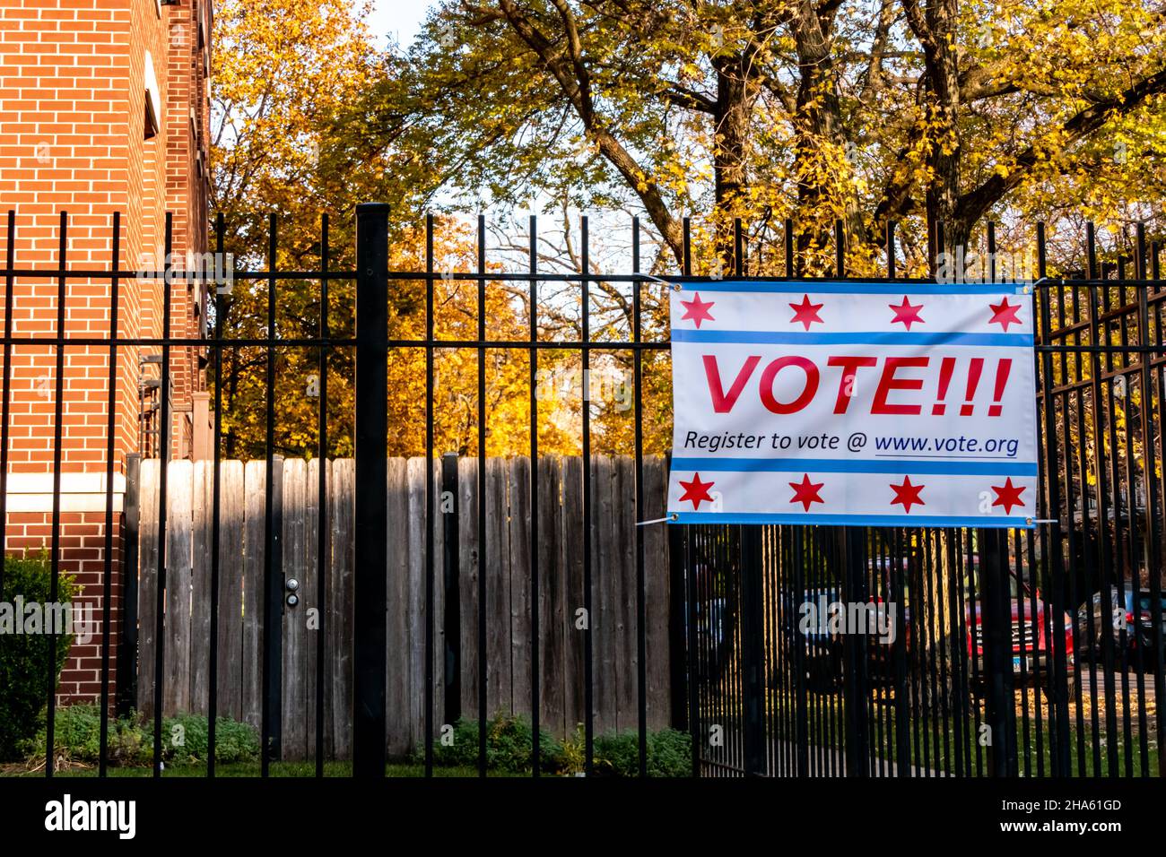 Register to Vote banner affixed to a black wrought iron fence, in a residential neighborhood. Stock Photo