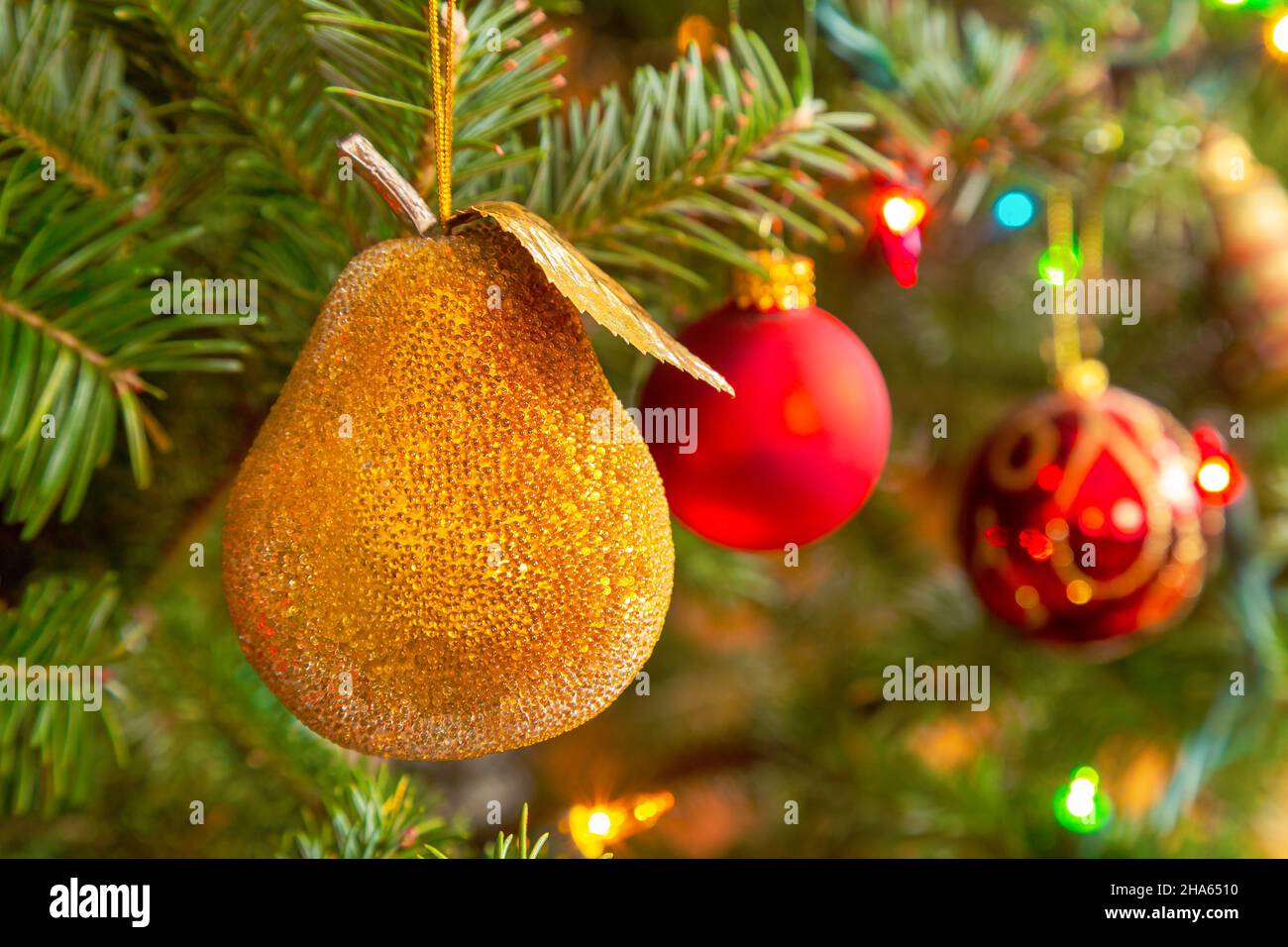 Sparkling glass pear hanging on a Christmas tree. Stock Photo
