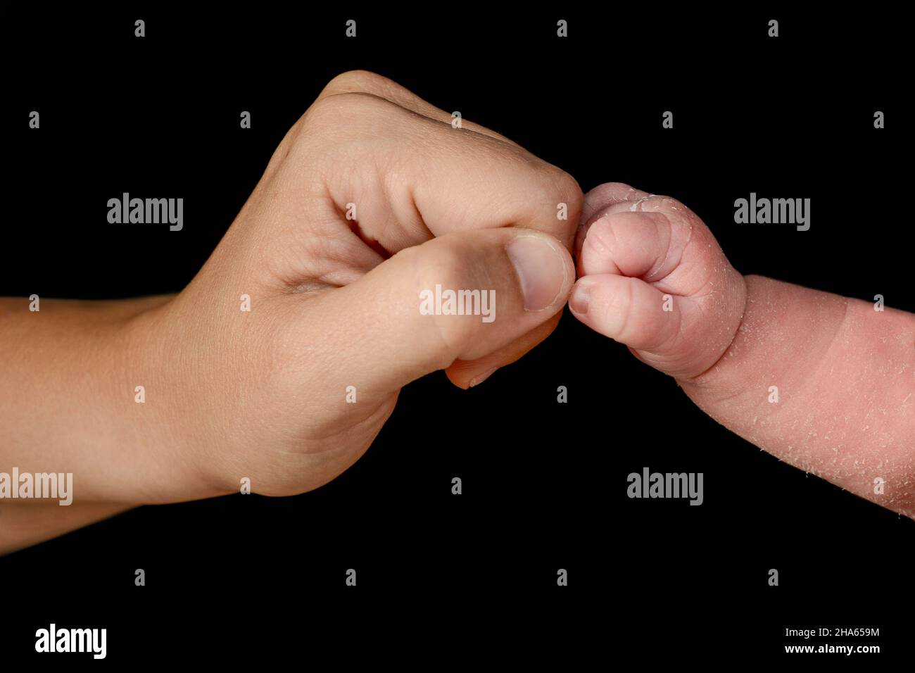 Small closed hand of newborn baby bumping his fist with his mother's
