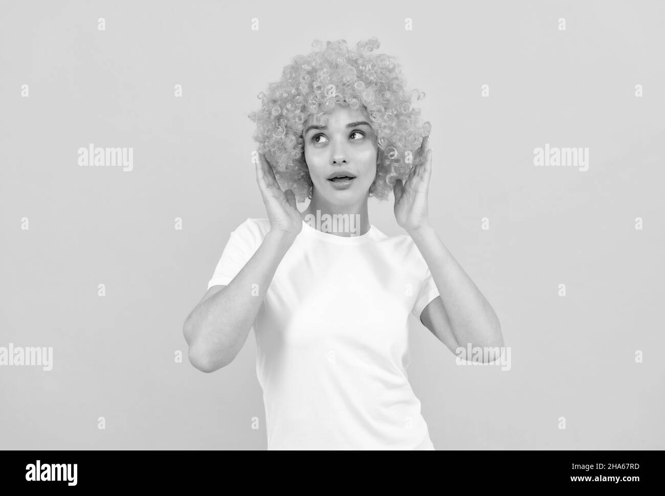 amazed fancy party look. freaky woman in clown wig on yellow background. express positive emotions. Stock Photo