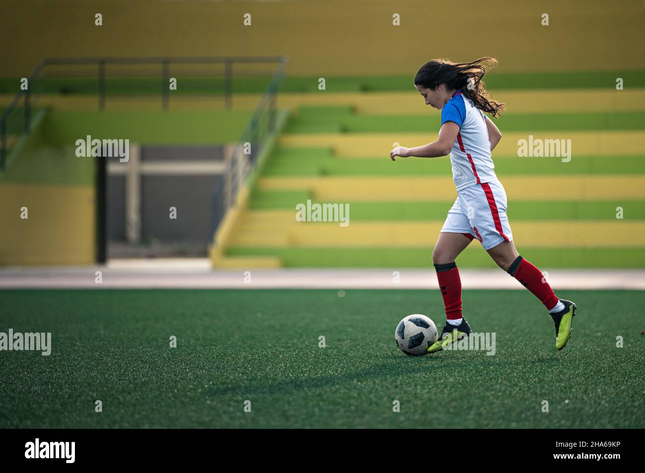 Young female soccer player kicks the ball on the field Stock Photo - Alamy