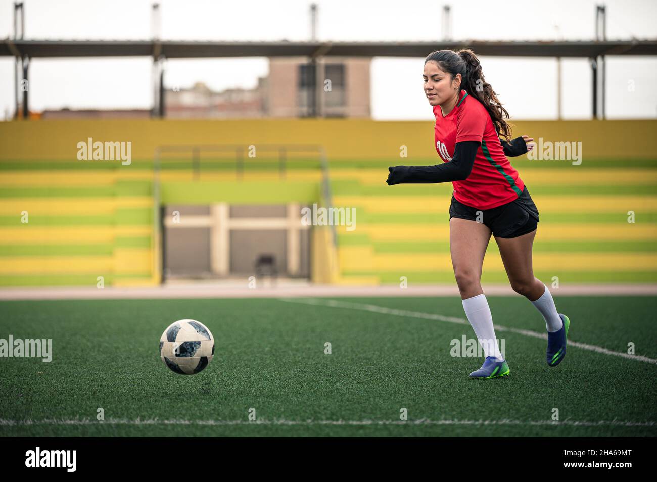 young female soccer player kicks the ball on the field Stock Photo