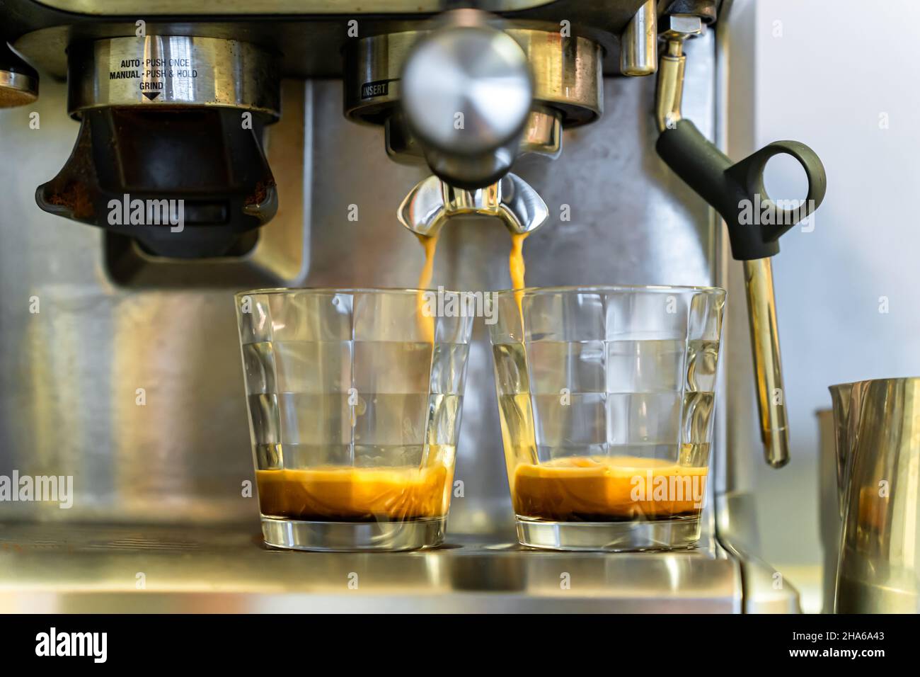 Espresso flows into two glasses from the holder of the coffee machine
