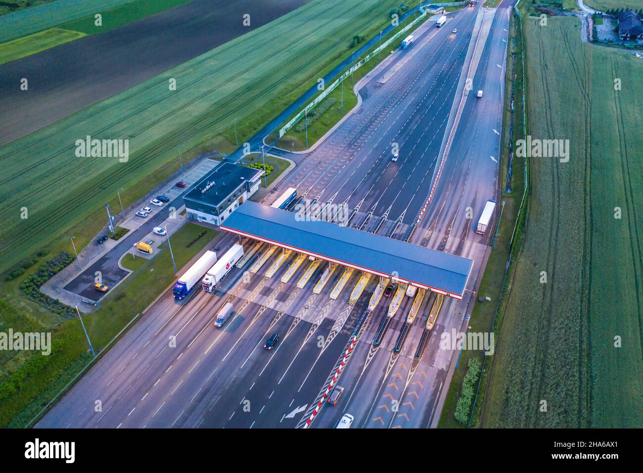 Car traffic transportation on multiple lanes highway road and toll collection gate, drone aerial top view at Night. Commuter transport, city life conc Stock Photo