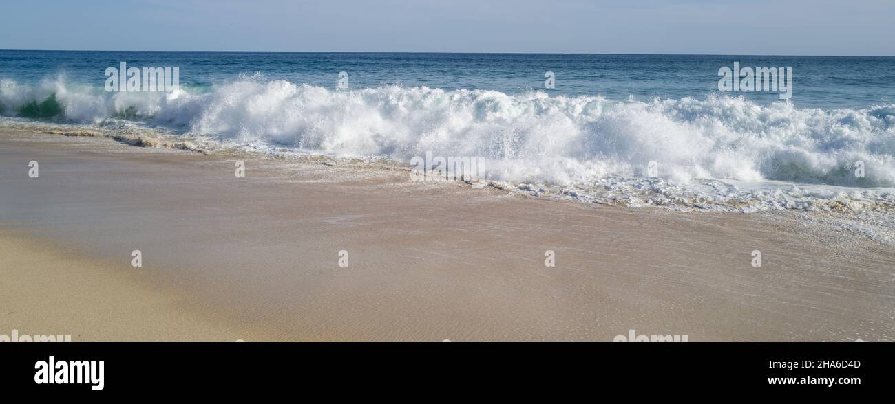 Ocean waves crashing on the beach under blue sky Stock Photo - Alamy
