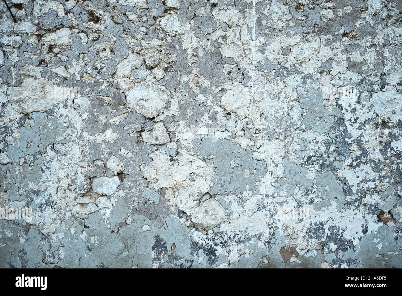 Old traditional limewashed stone wall with peeling plaster, white rustic background or texture Stock Photo