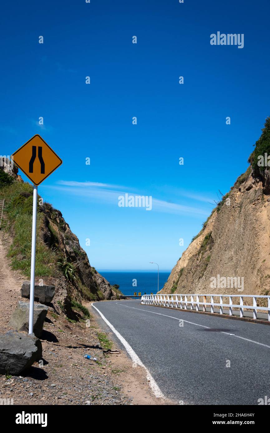 Narrow road through cutting to sea, Pass of Branda, Seatoun, Wellington, North Island, New Zealand Stock Photo