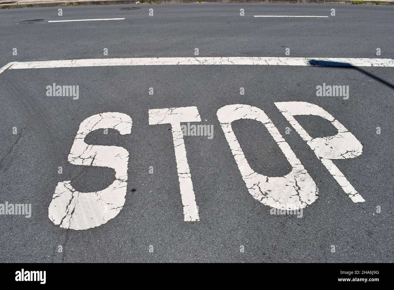 stop sign painted on a asphalt road surface Stock Photo