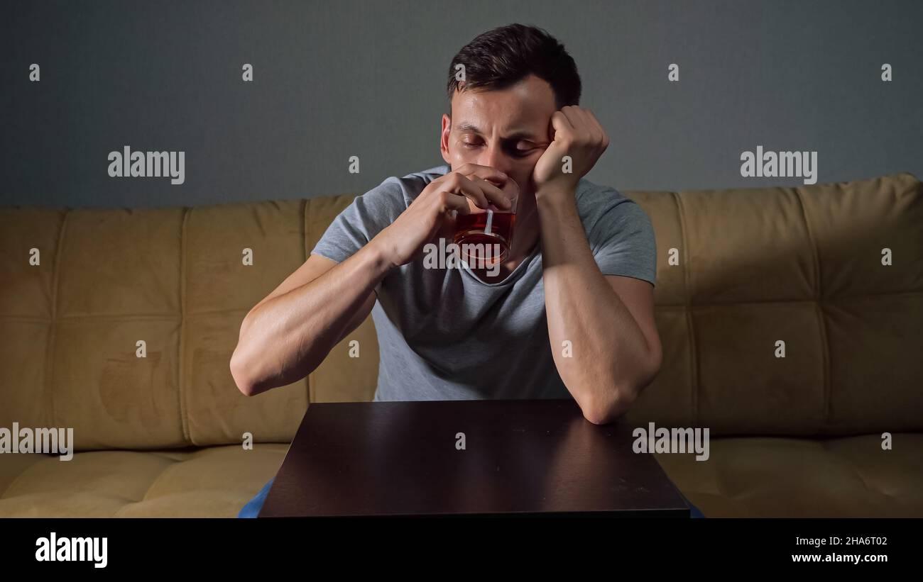Young tipsy man drinks alcohol trying to solve problems Stock Photo