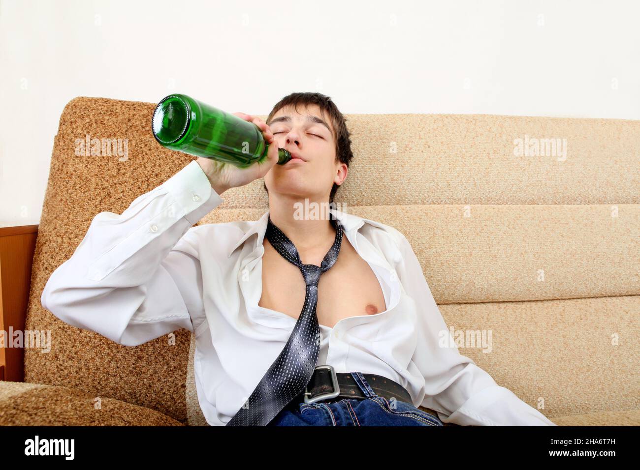 Teenager drinks a Beer on the Sofa at the Home Stock Photo