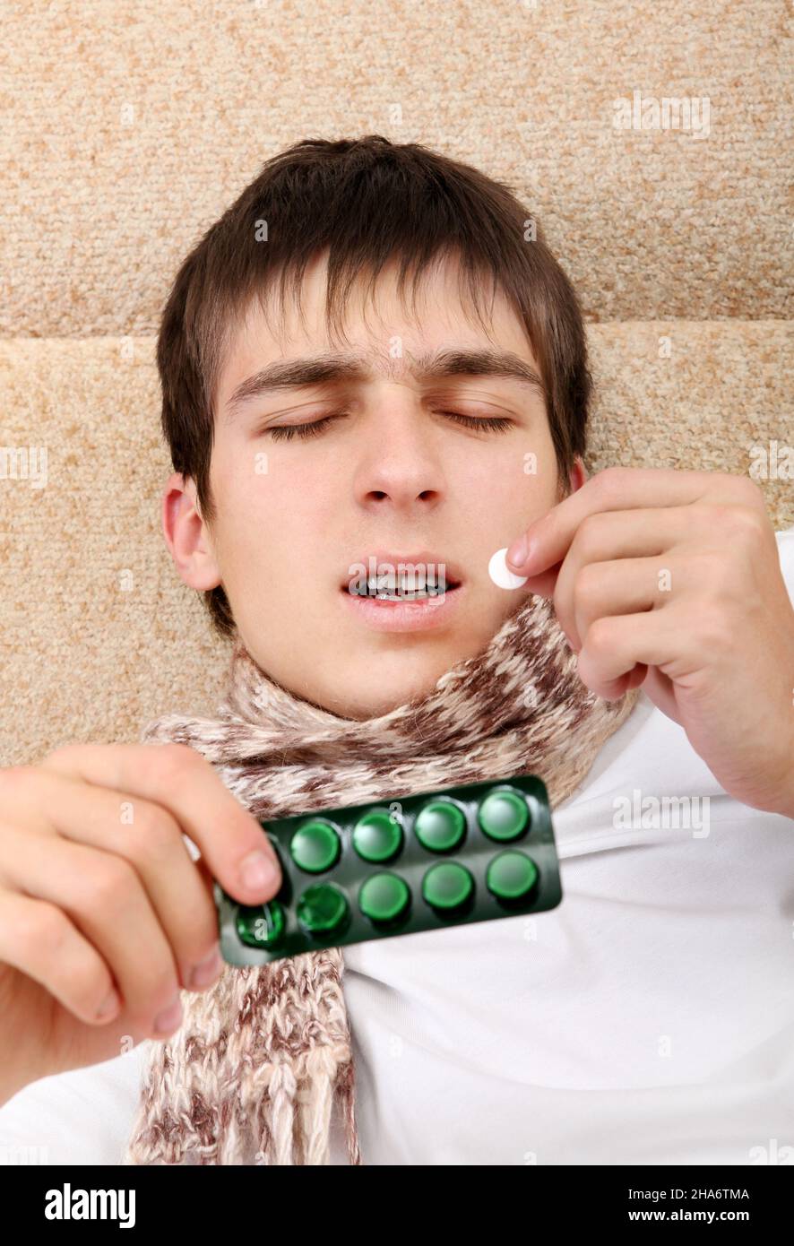Sick Teenager taking a Pill on the Bed at the Home Stock Photo