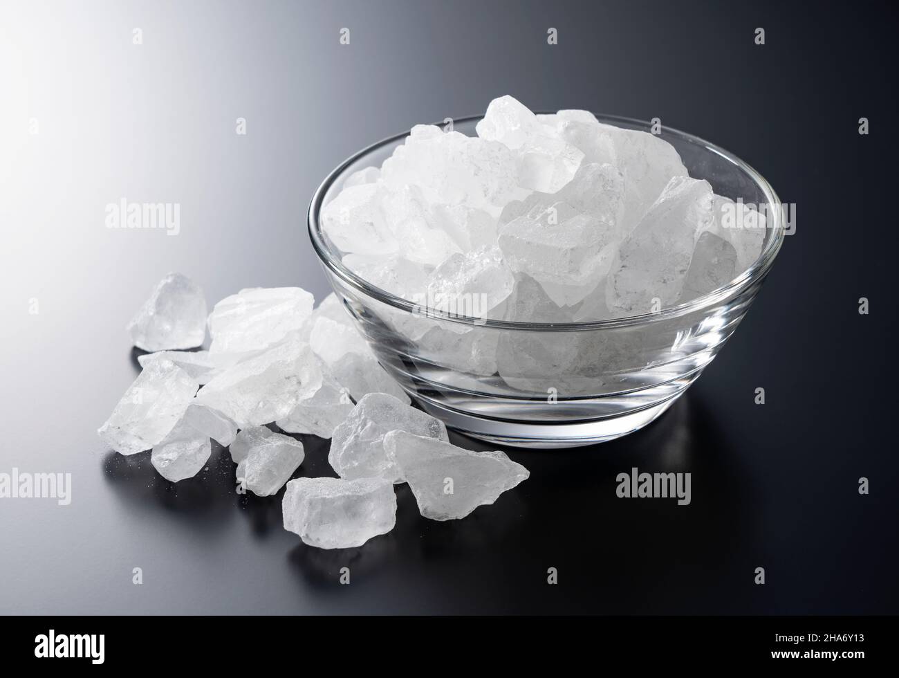 rock candy in a glass bowl set against a black background. Stock Photo