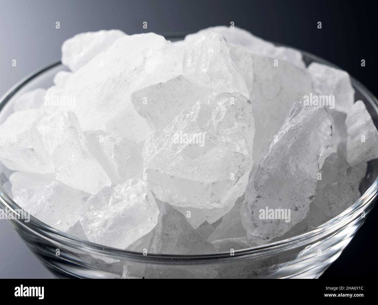 rock candy in a glass bowl set against a black background. Stock Photo