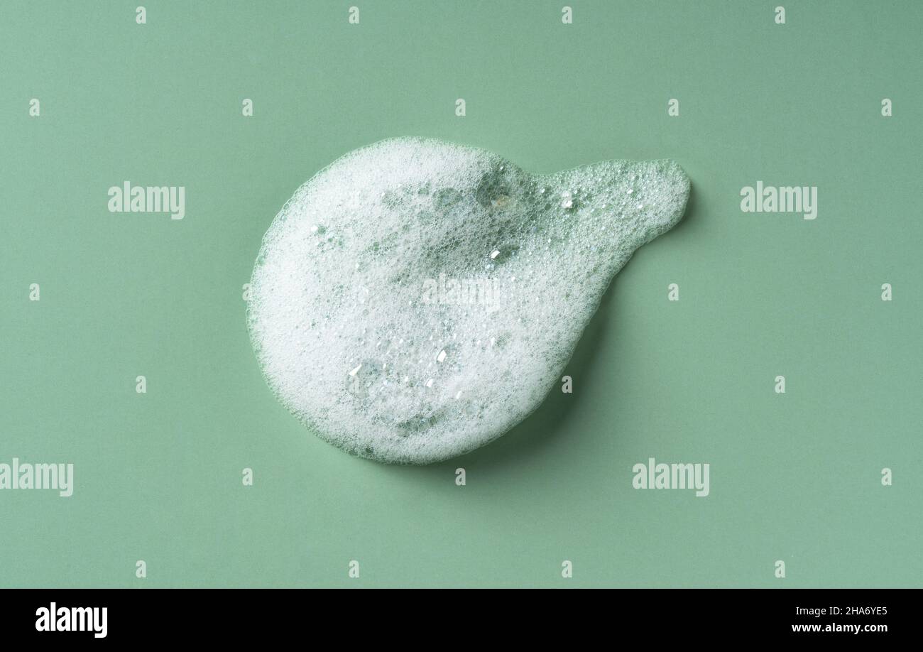 Foam texture on green background. Soap, shampoo, mousse, shower gel
