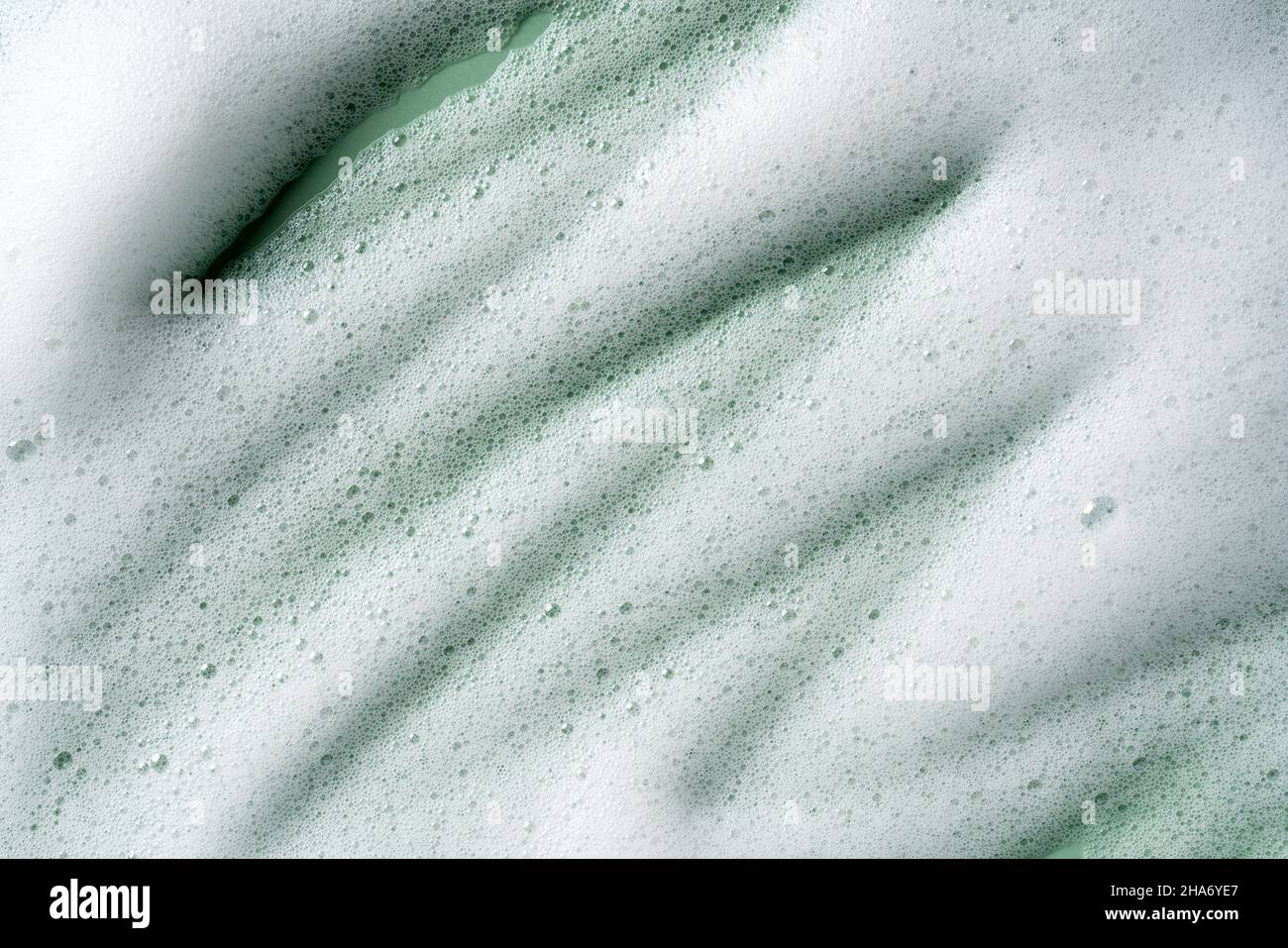 Bubbles texture background on green background. Soap, shampoo, mousse, shower gel foam. Stock Photo