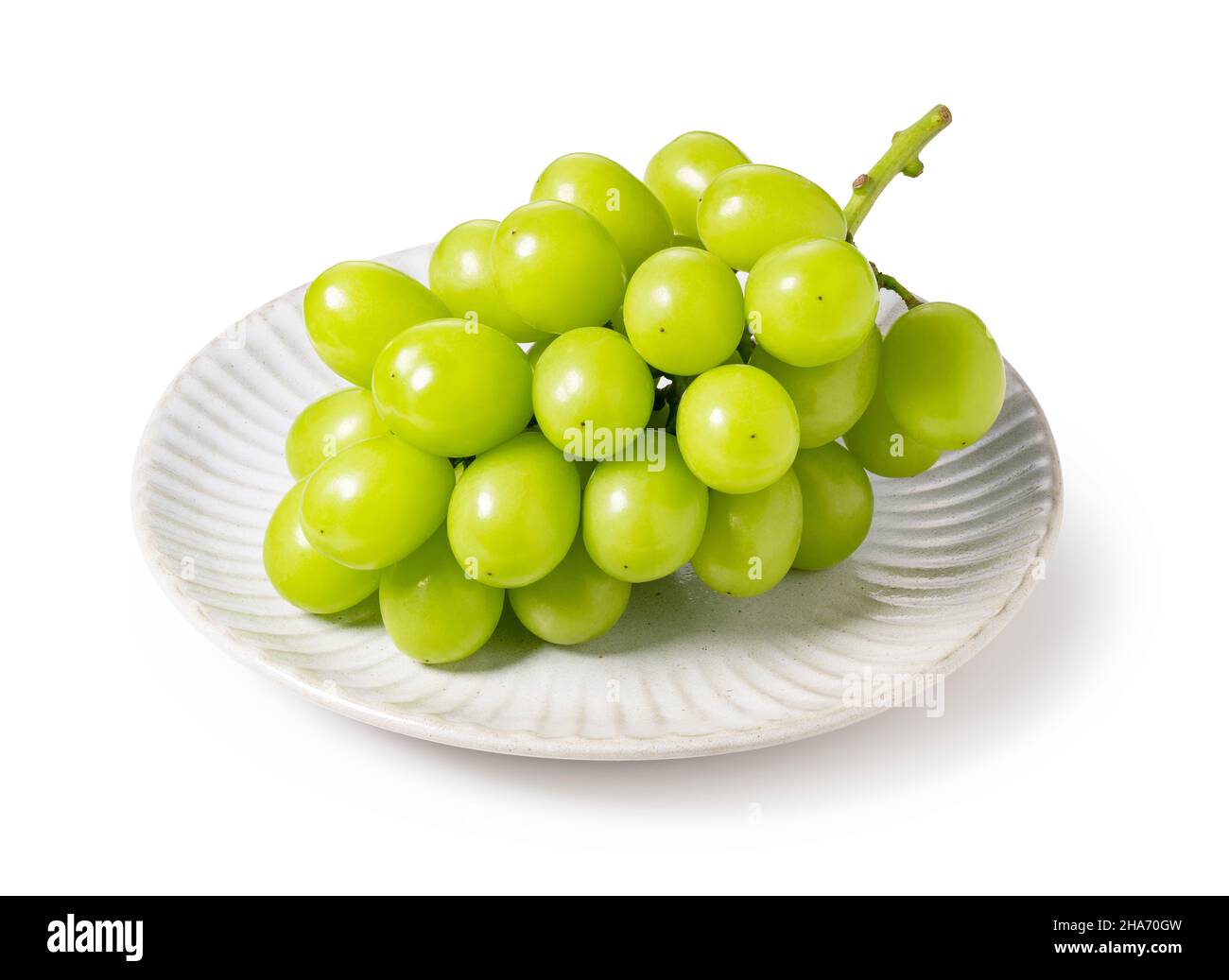 Bunch of Schein Muscat grapes on a plate set against a white background. White grapes. Japanese grapes. Stock Photo