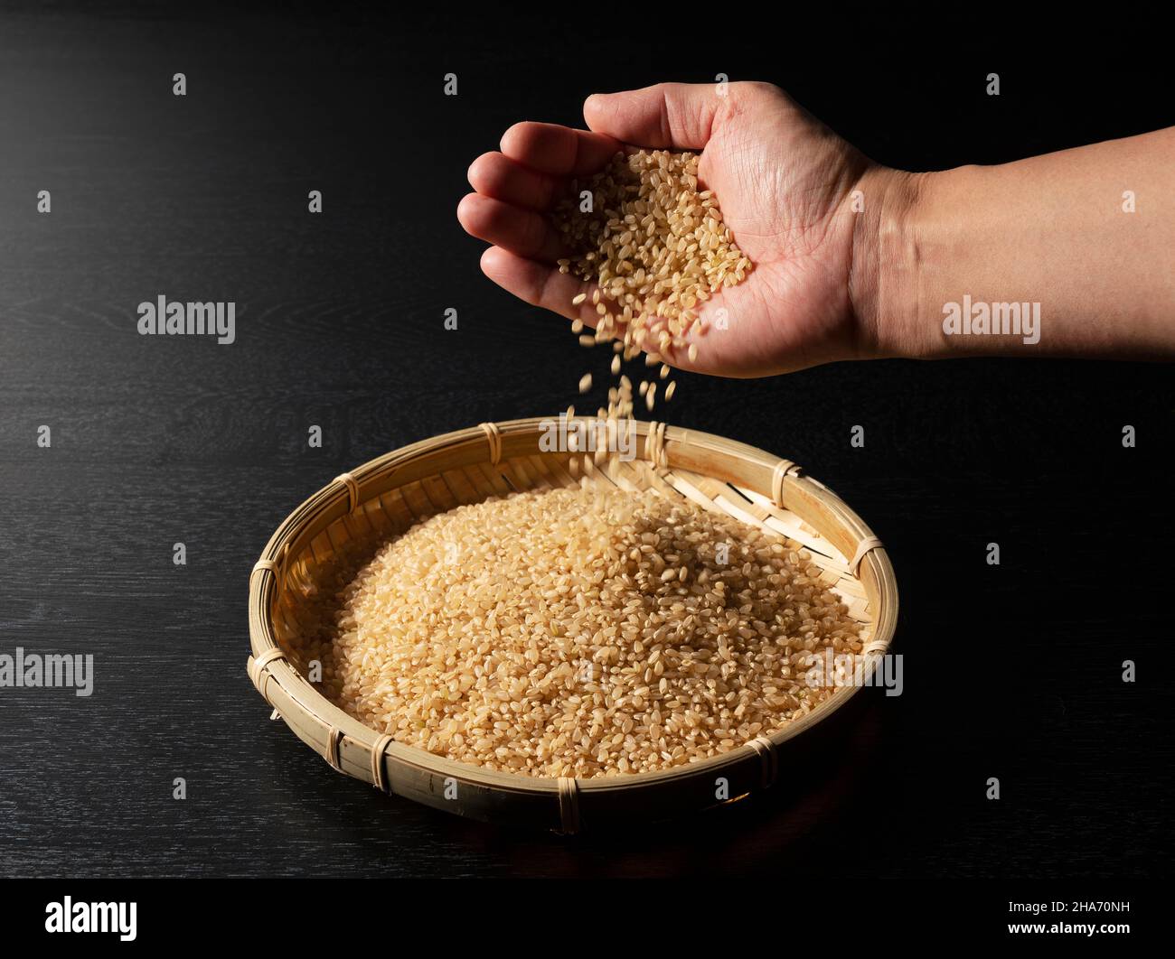 The moment when a man pours brown rice into a bamboo colander placed on ...