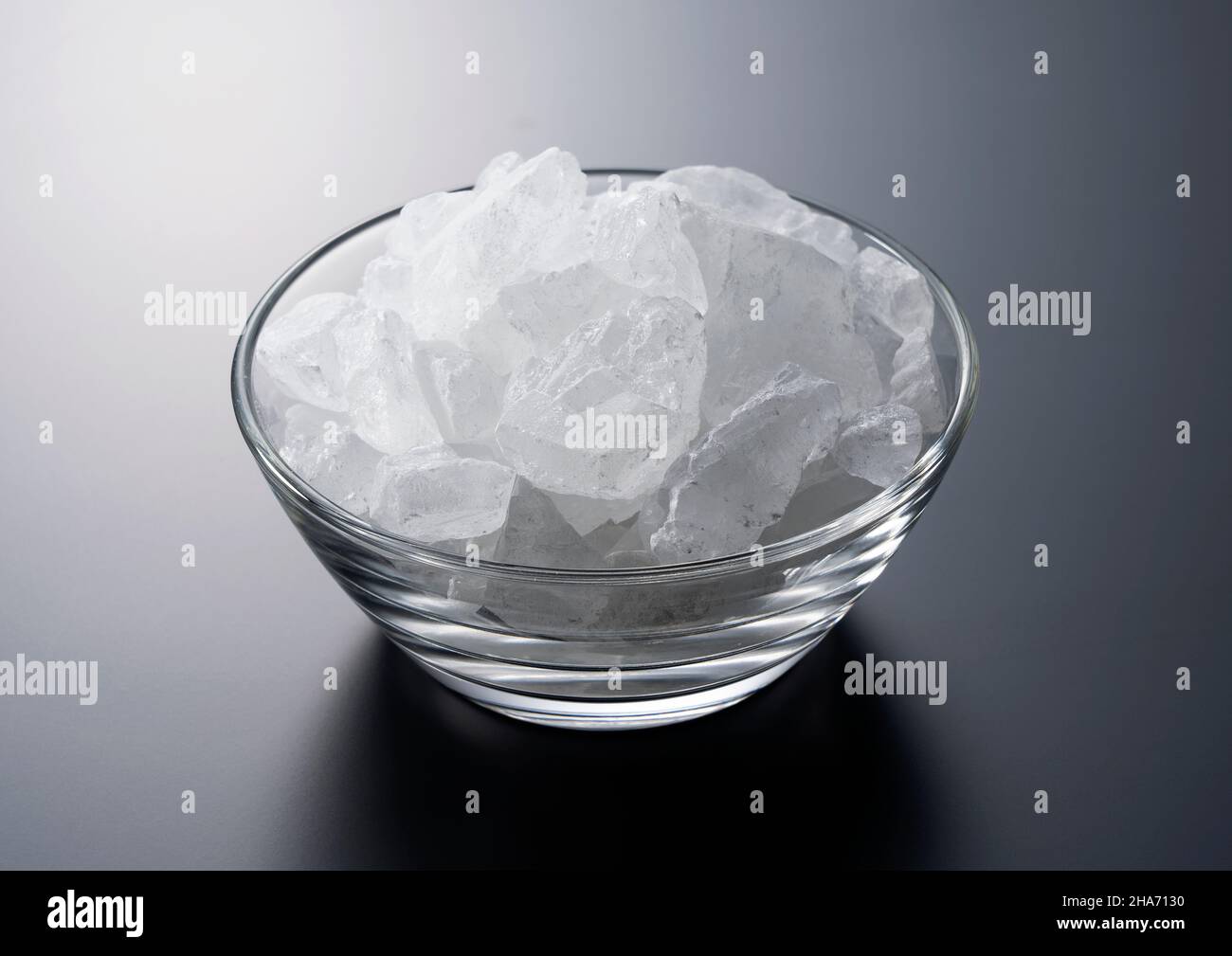 rock candy in a glass bowl set against a black background. Stock Photo