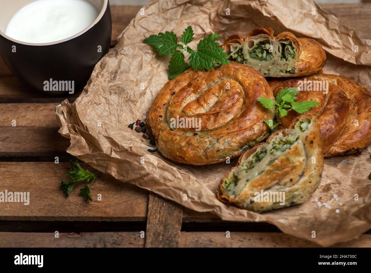 Homemade vegan mini pie in the shape of a snail. with nettle on a rustic wooden background. Vegan food. Stock photo. Stock Photo