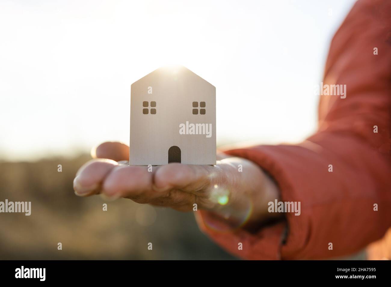 Close-up of female hand holding wooden white house model with autumn ...