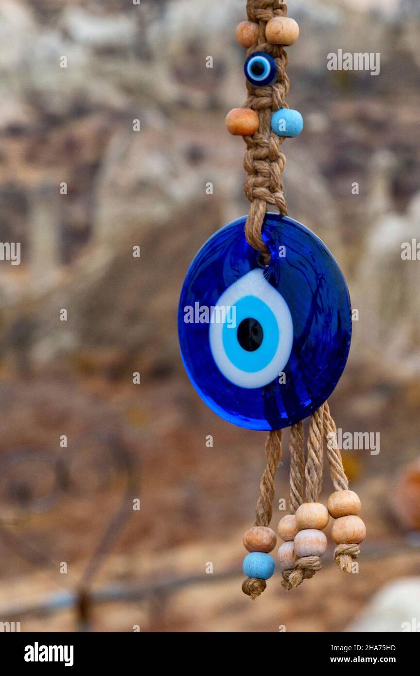 Close up view of evil eye beads nazar boncuguor eye of fatima hanging down in Cappadocia, Nevsehir, Turkey. There is only rocks in back. Selective foc Stock Photo