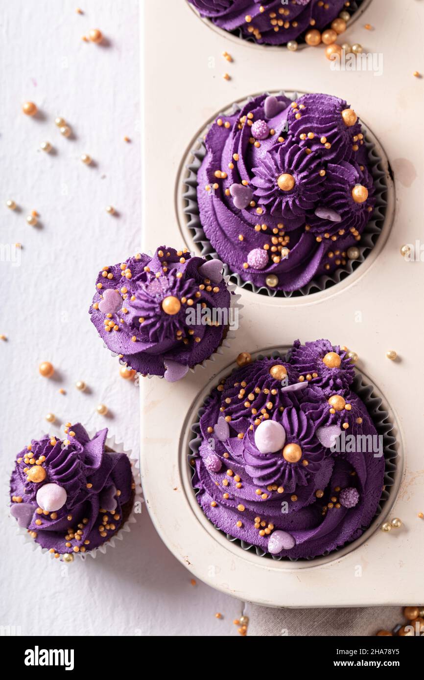 Tasty cupcakes with violet cream ready to eat. Purple dessert with golden  sprinkles in baking tray Stock Photo - Alamy, image size:866x1390