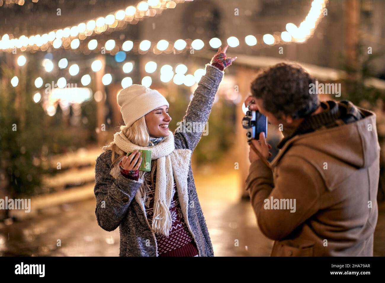 Happy girl  enjoying at christmas festival on a snowy weather and man take picture Stock Photo