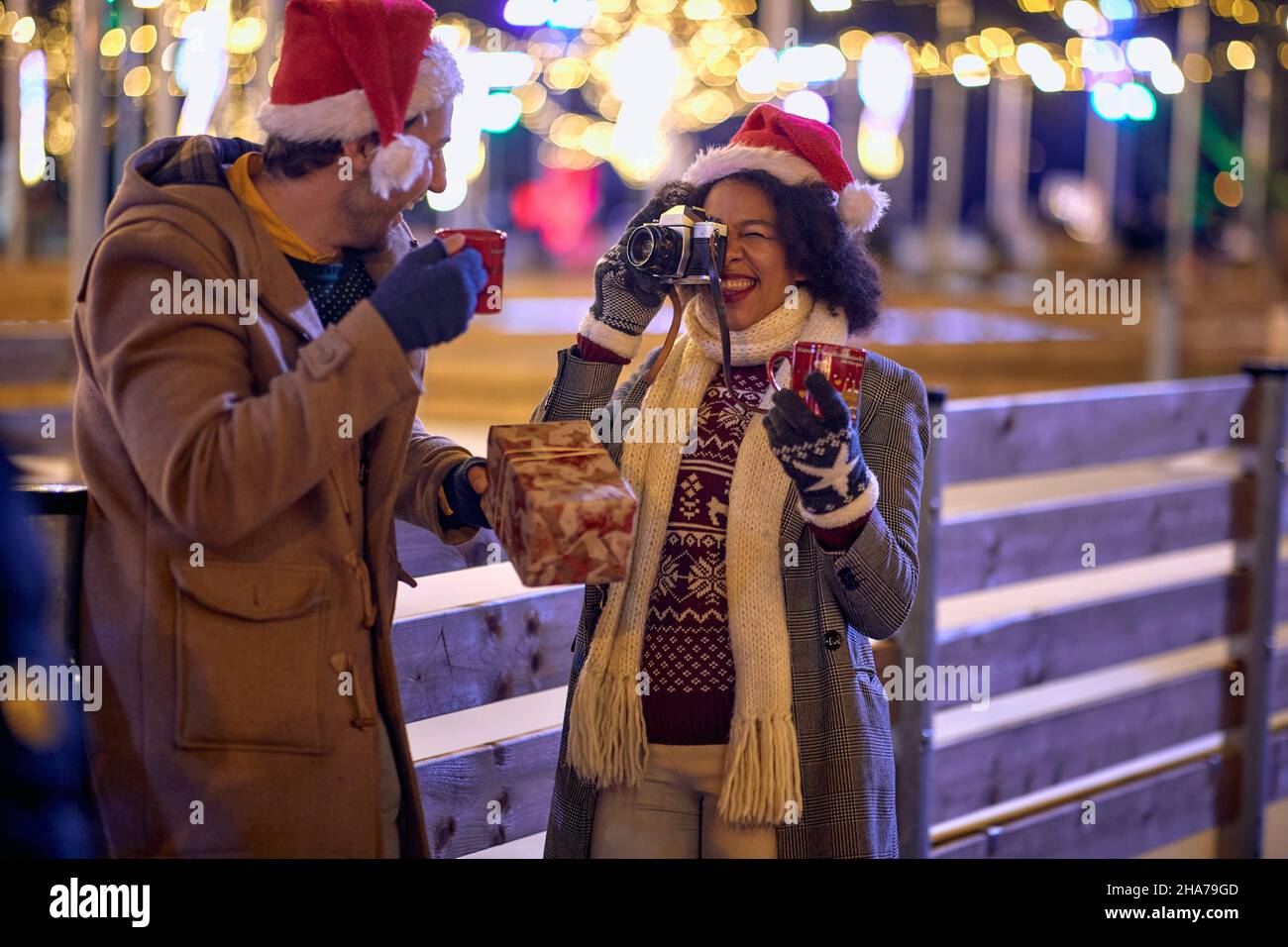 Woman taking a photo smiling boyfriend at christmas festival on a snowy weather Stock Photo