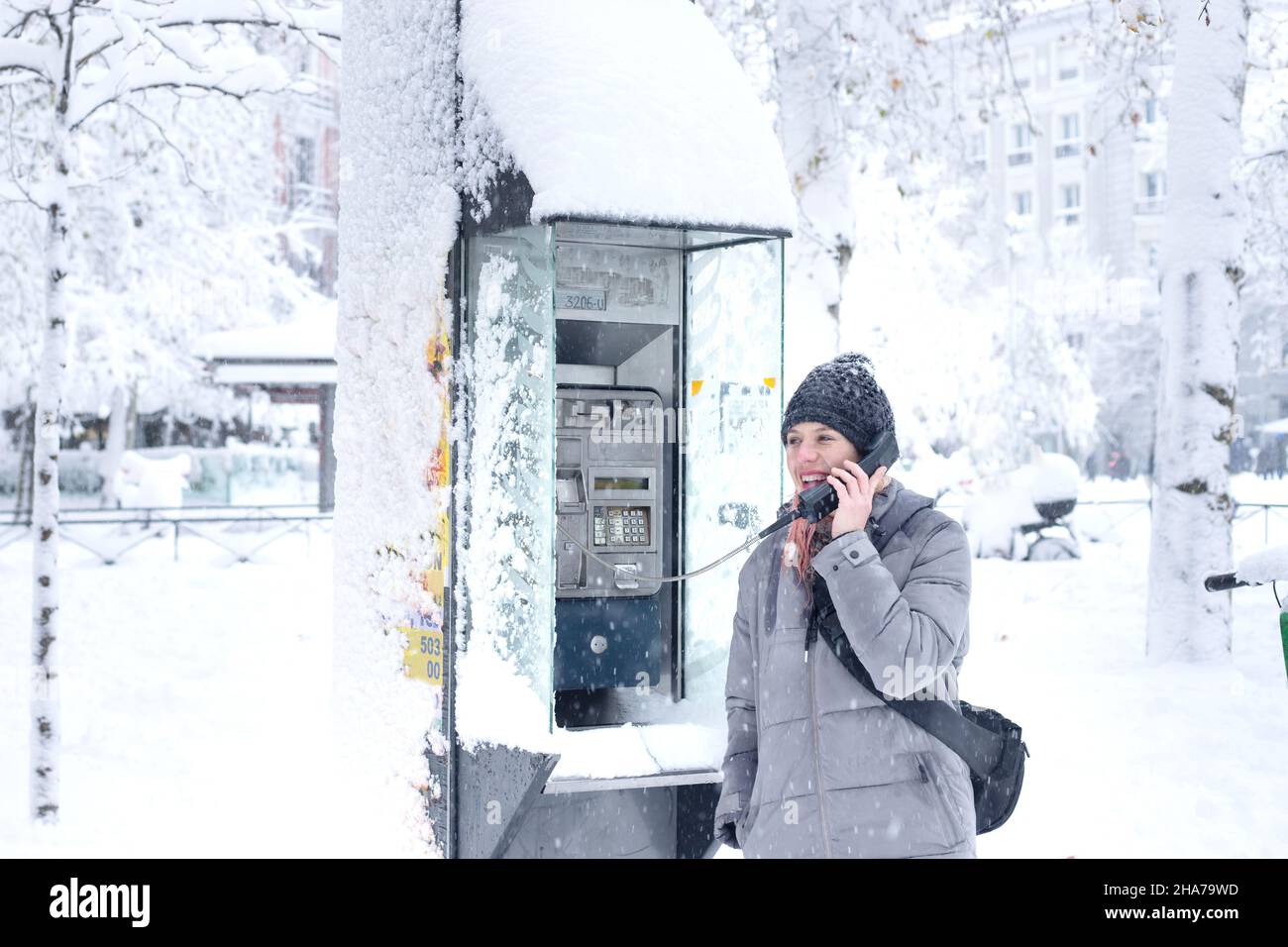 woman talking in a public phone booth on a day completely covered with snow Stock Photo