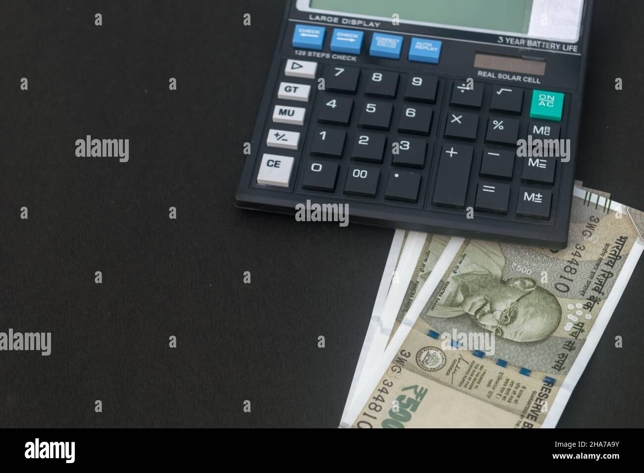 Indian Rupee placed under a calculator on table. Isolated on black ...