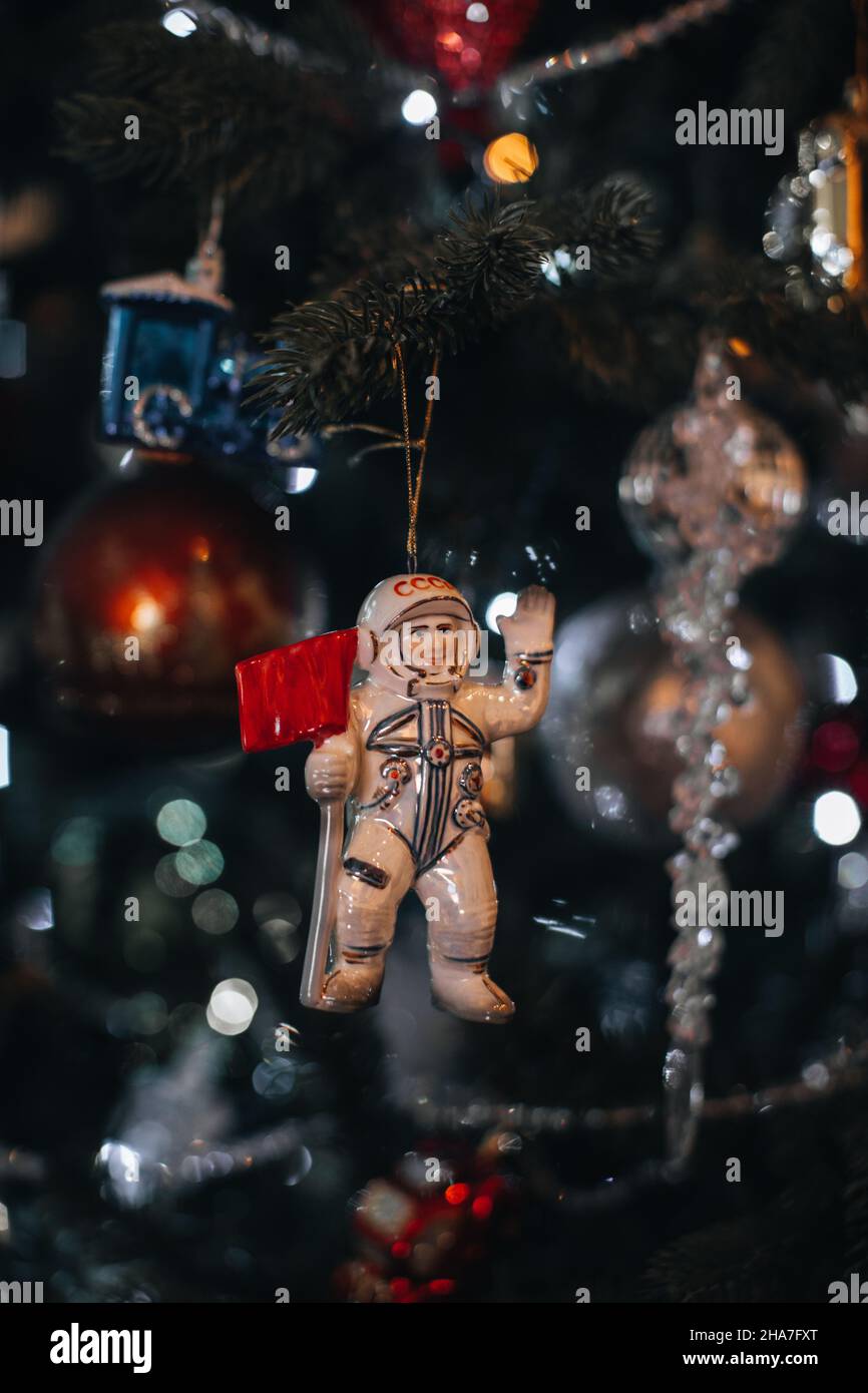 Christmas tinny toy white Russian cosmonaut hanging on the Christmas tree. Festive decor, New Year winter details Stock Photo