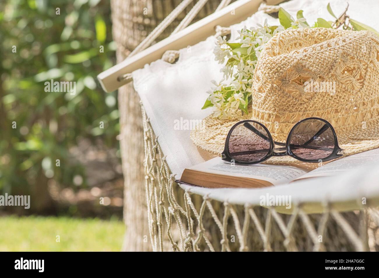 Straw hat on a hammock in a sunny summer day. Rest in the garden. Summer time fun Stock Photo