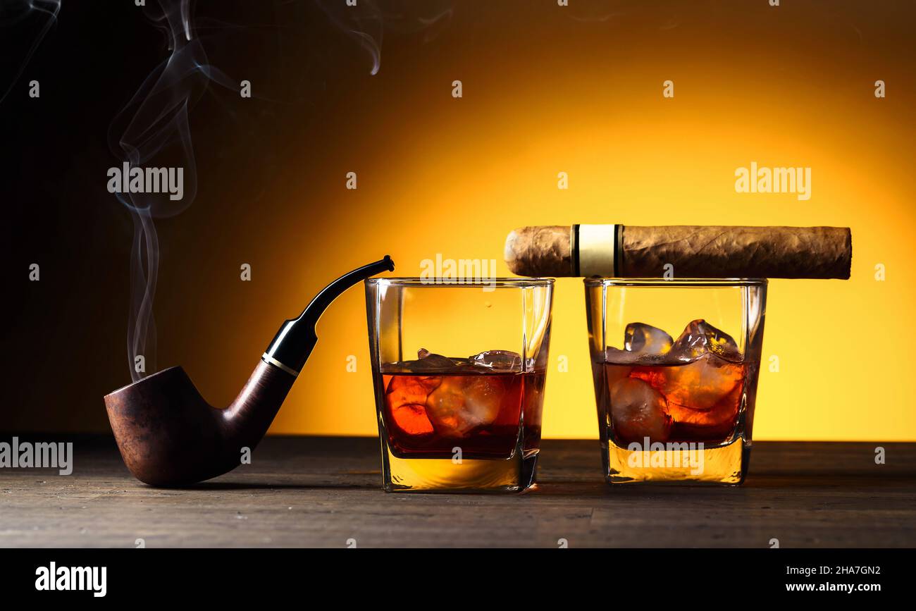 Glasses of whiskey, pipe, and cigar on a wooden table. Copy space Stock